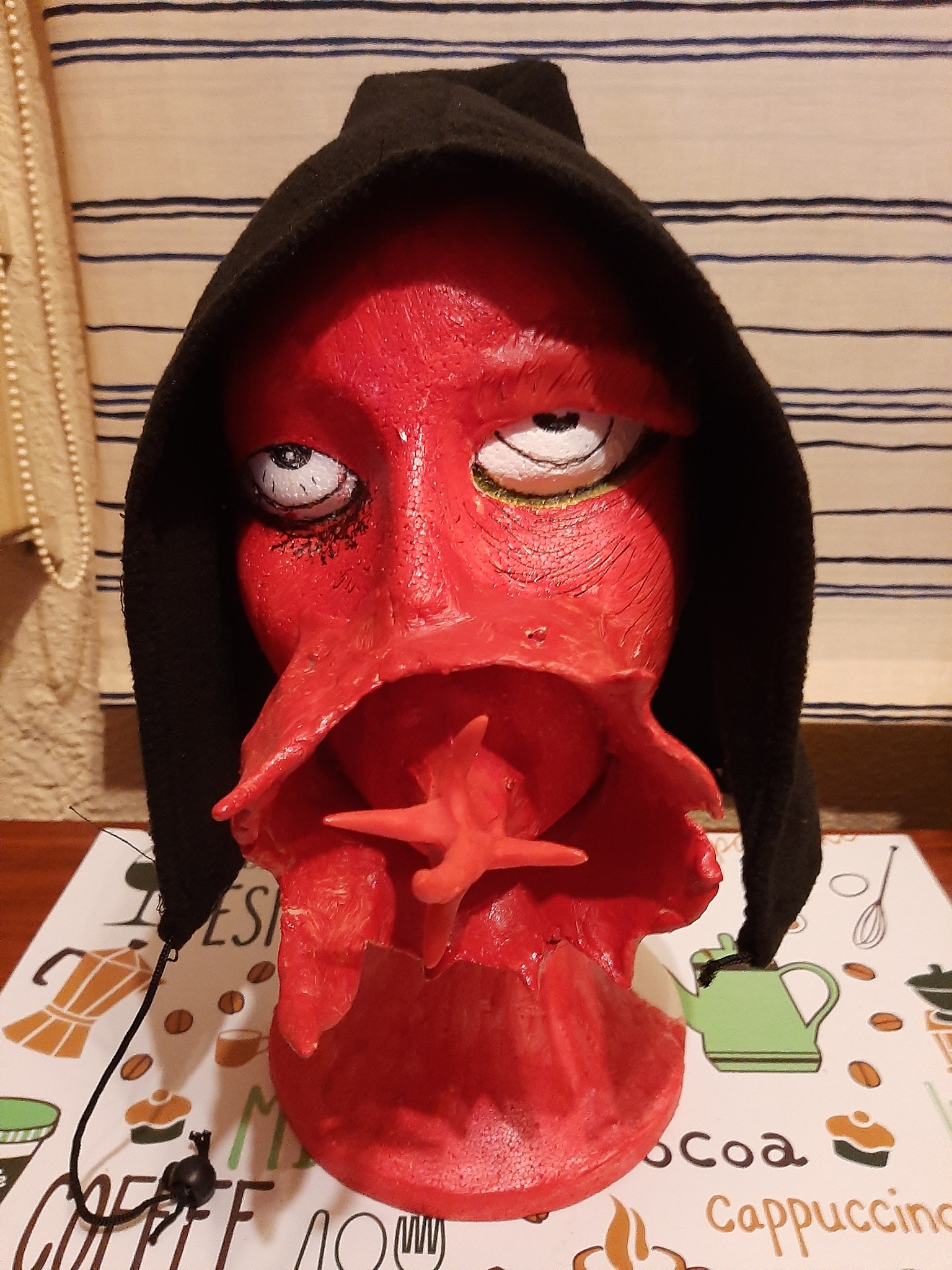 El alarido del diablo, avatar escultórico rojo con capucha negra